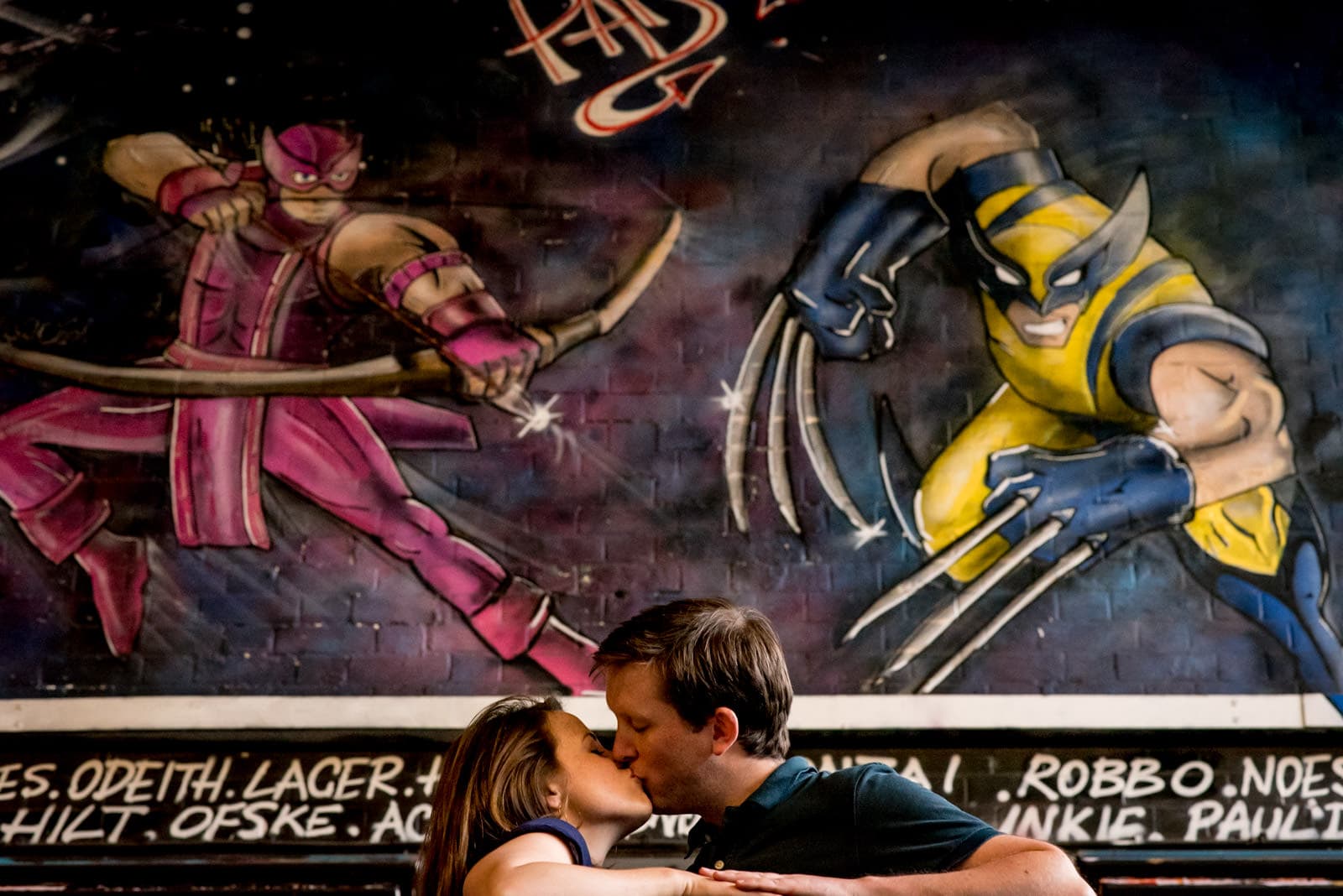 Photo of couple kissing during their Vaults London engagement shoot with graffiti of Wolverine and Hawk Eye