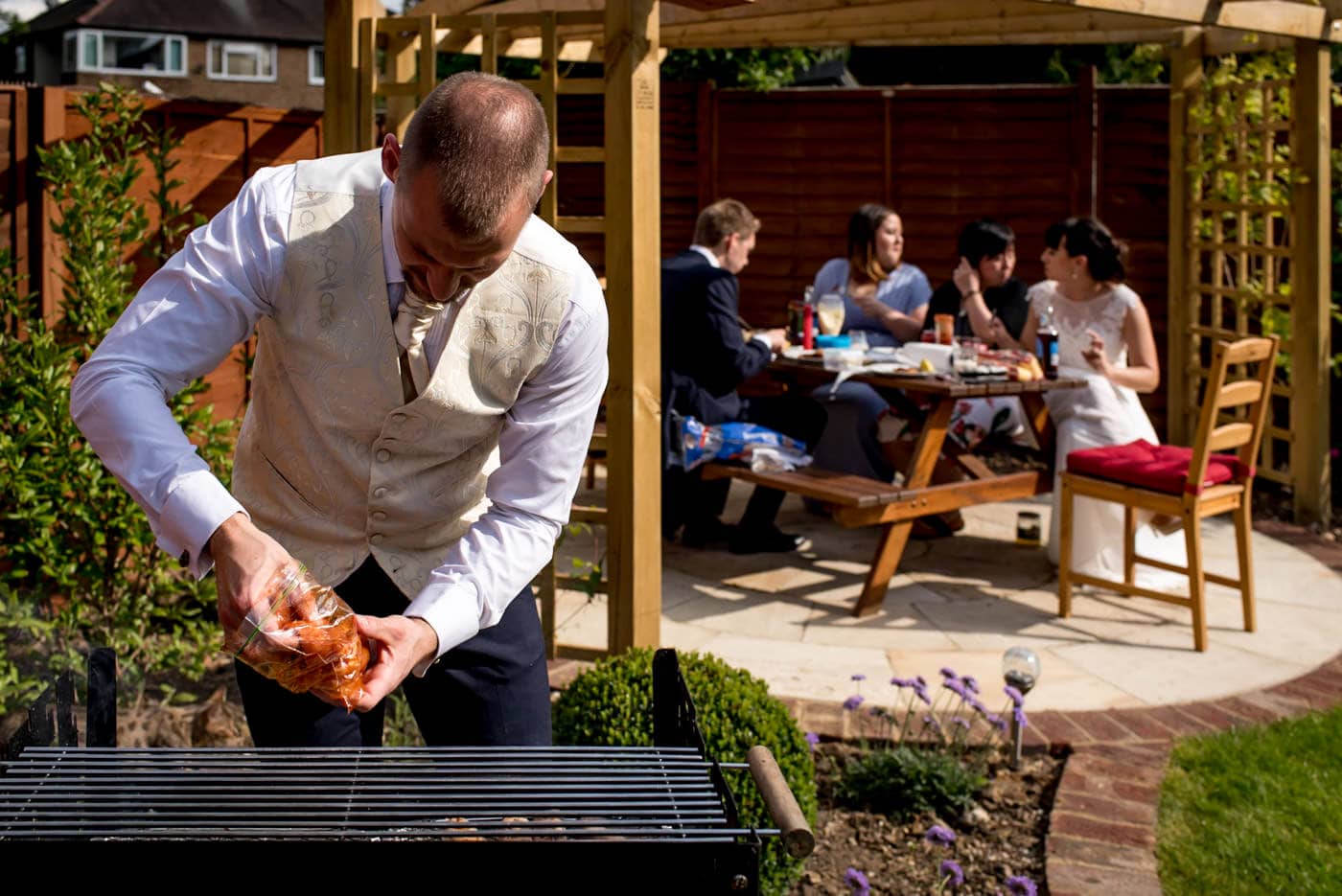 groom cooking a BBQ for his guests at his intimate garden wedding in London