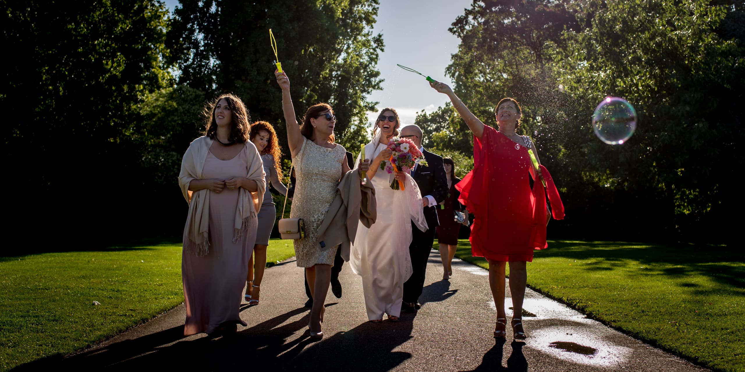 bridal party walking through Regents park with bubbles as part of their intimate London wedding celebrations
