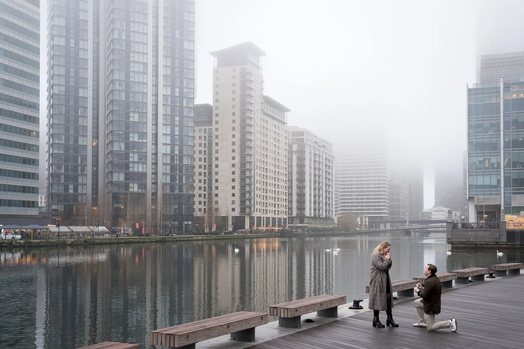 A man proposing to his girlfriend in Canary Wharf on a misty winter's morning in London