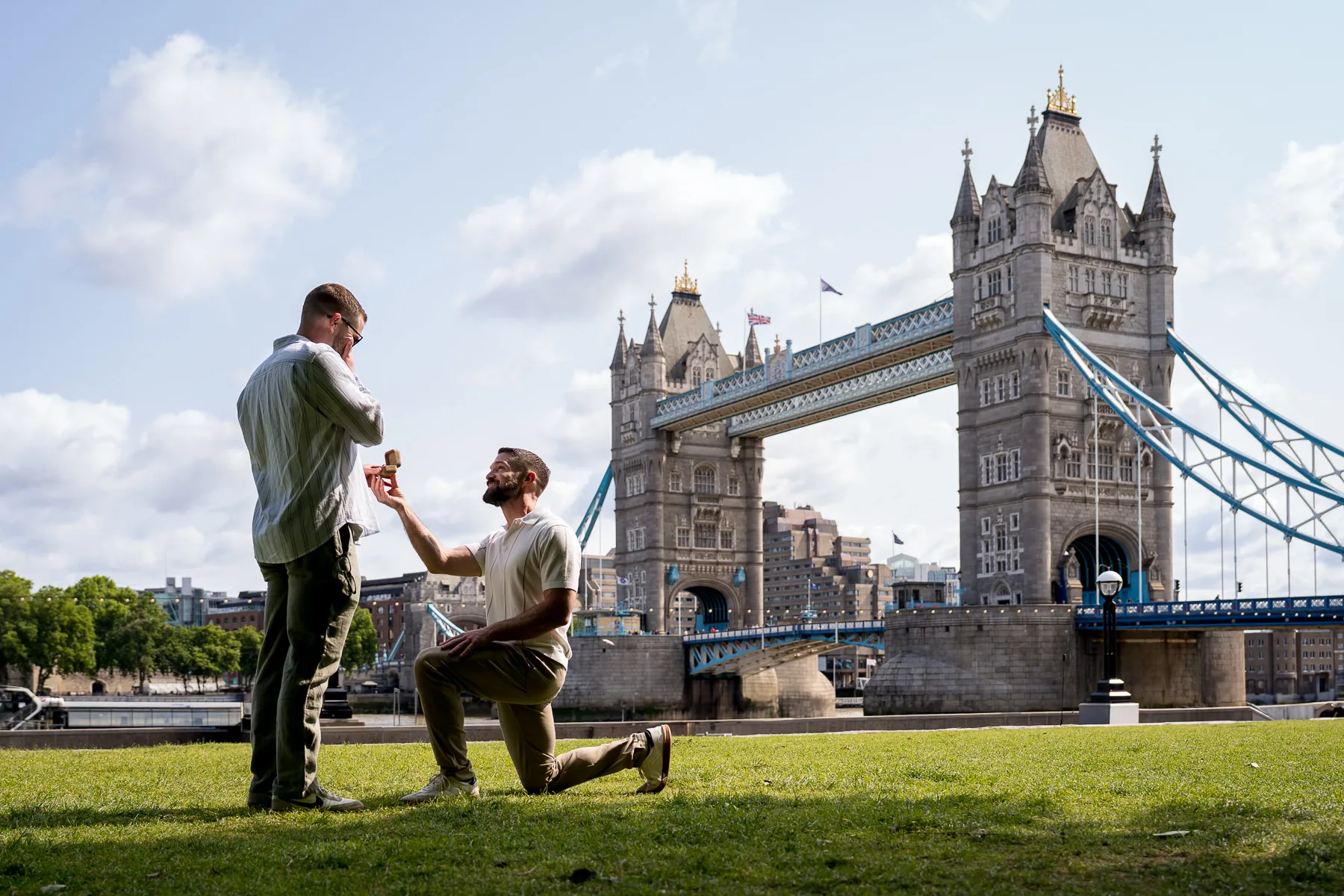 A same sex couple proposing in London with Tower Bridge in the background