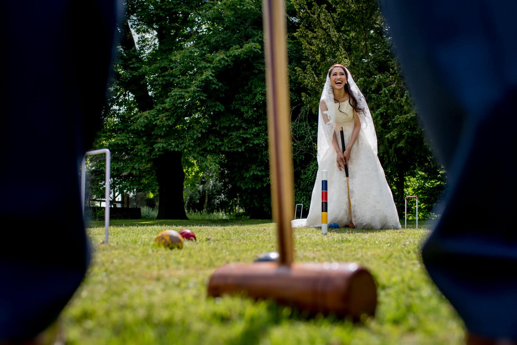 a bride in her wedding dress playing croquet in the sun and laughing taken by London wedding photographer Matt Badenoch
