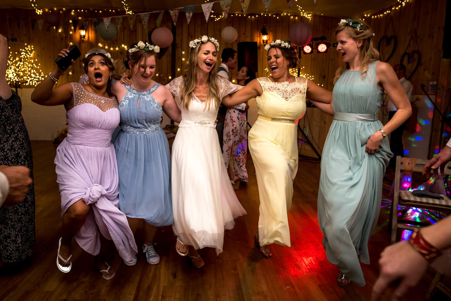 bride dancing with her bridesmaids in colourful dresses at her wedding