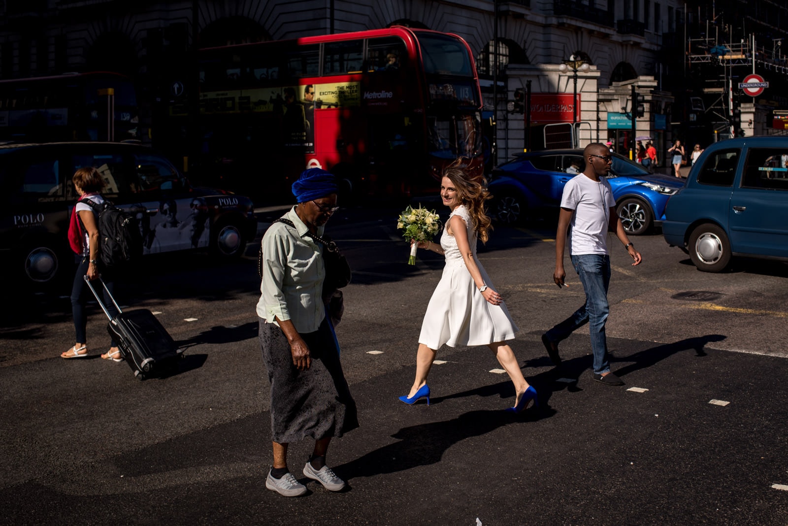 photo of bride in wedding dress walking across the street in London with a red bus in background.