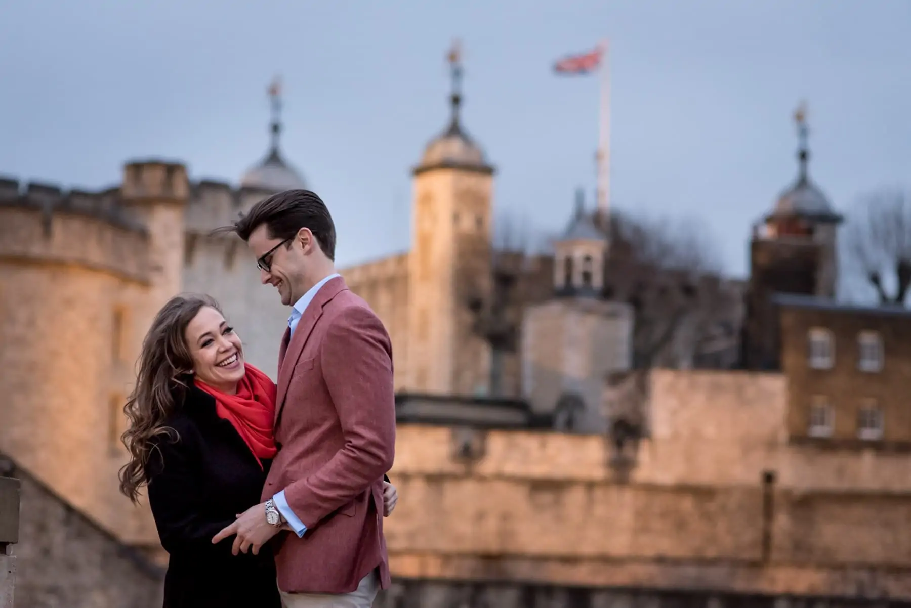 a couple laughing on their london proposal shoot in front of the Tower of London