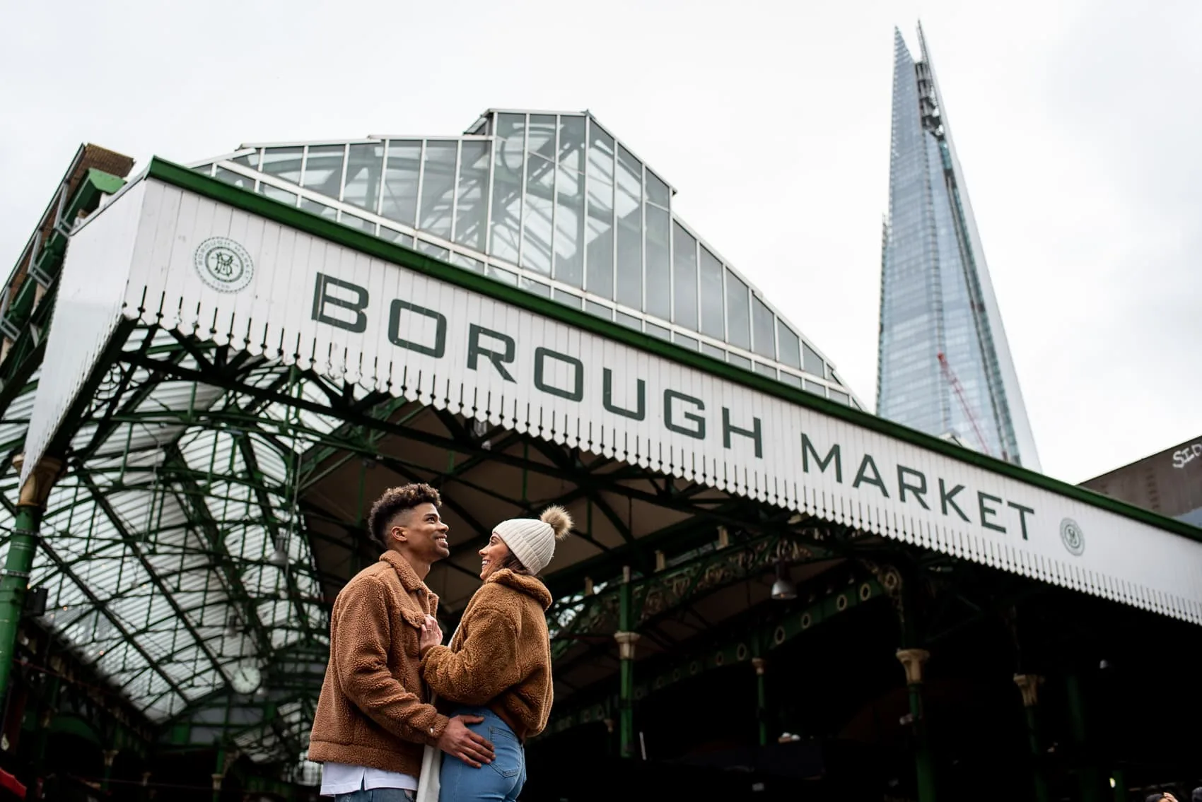 Recently engaged couple posing in front of Borough Market and the Shard on their London proposal shoot