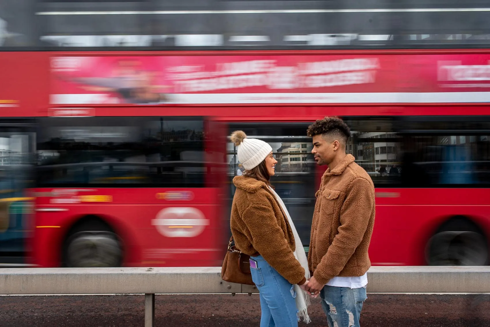 Couple posing in front of red London bus as it speeds past. Taken using motion blur