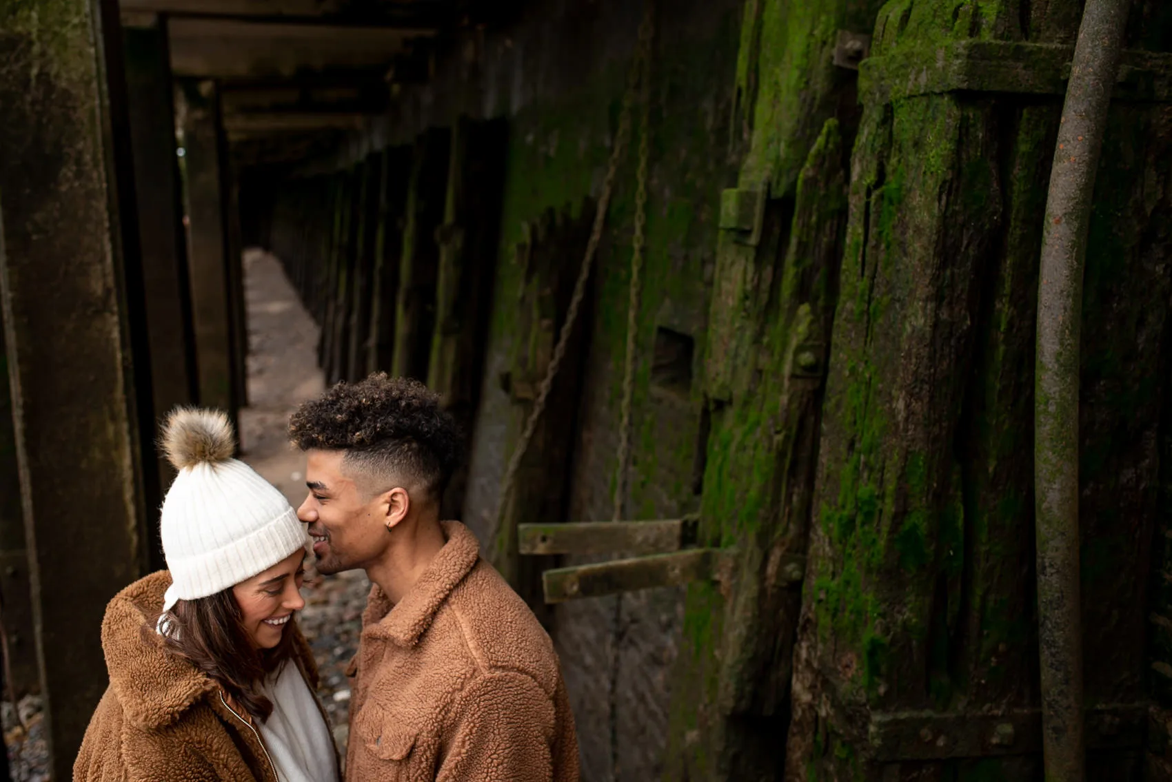 Couple kissing by green wood on thames beach at low tide
