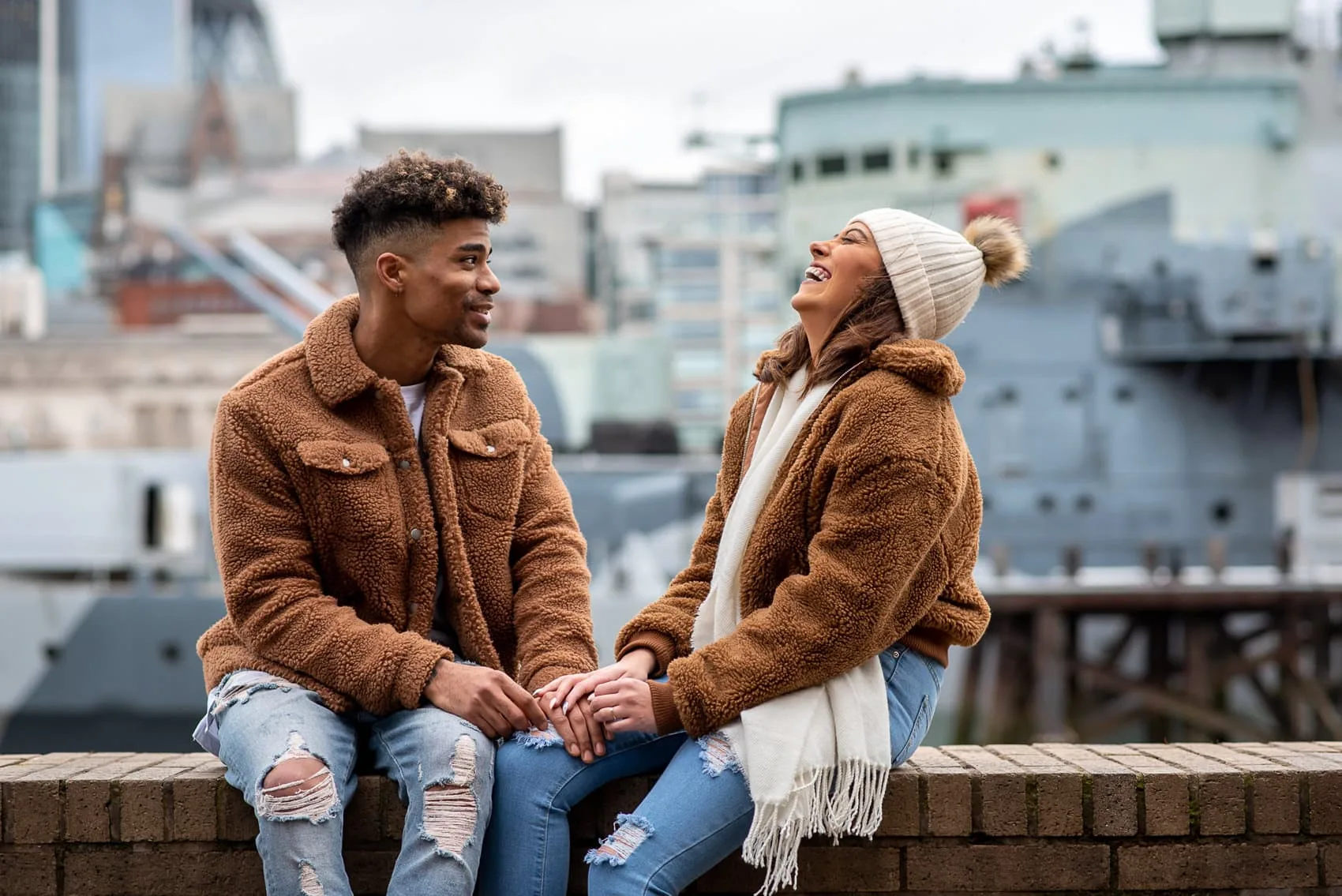 Engaged couple laughing in front of the HMS Belfast