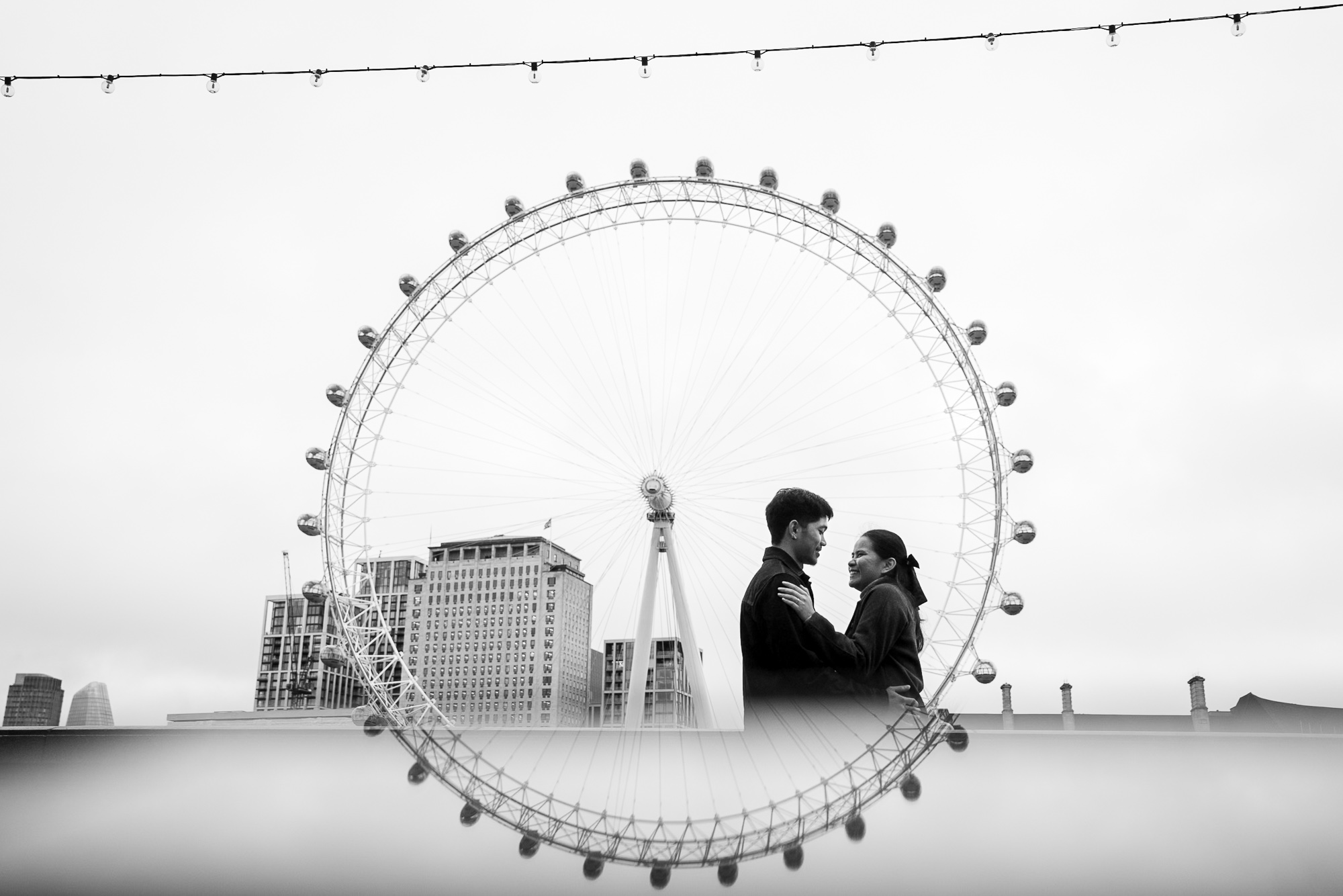 The London Eye in a reflection to make a full circle with an engaged couple
