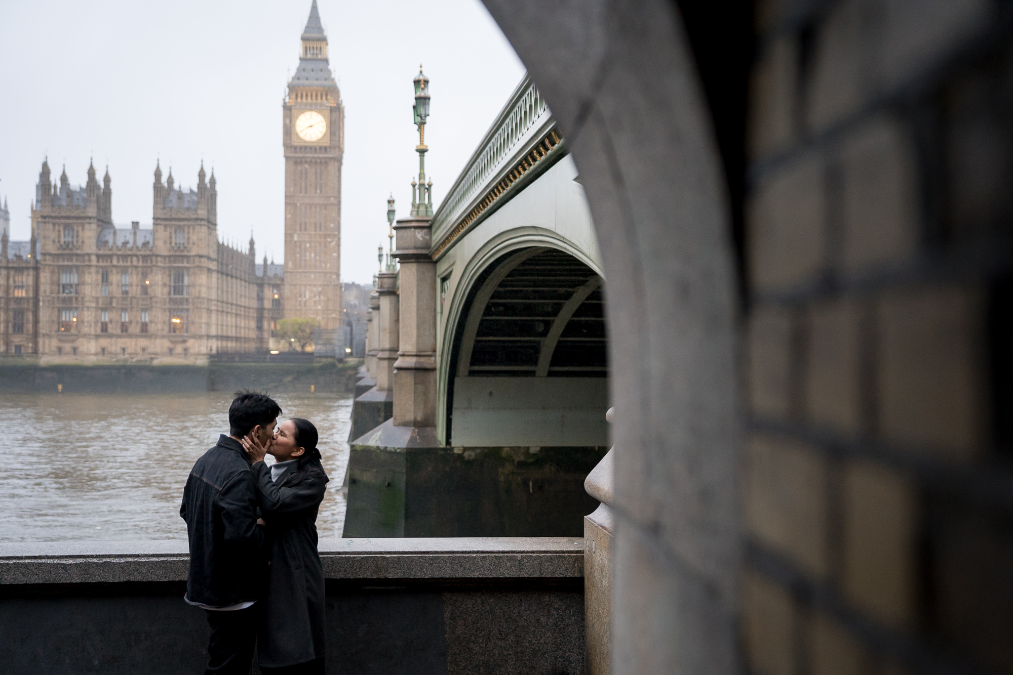 A couple share a kiss in front of Big Ben on a winter's morning during their London proposal shoot