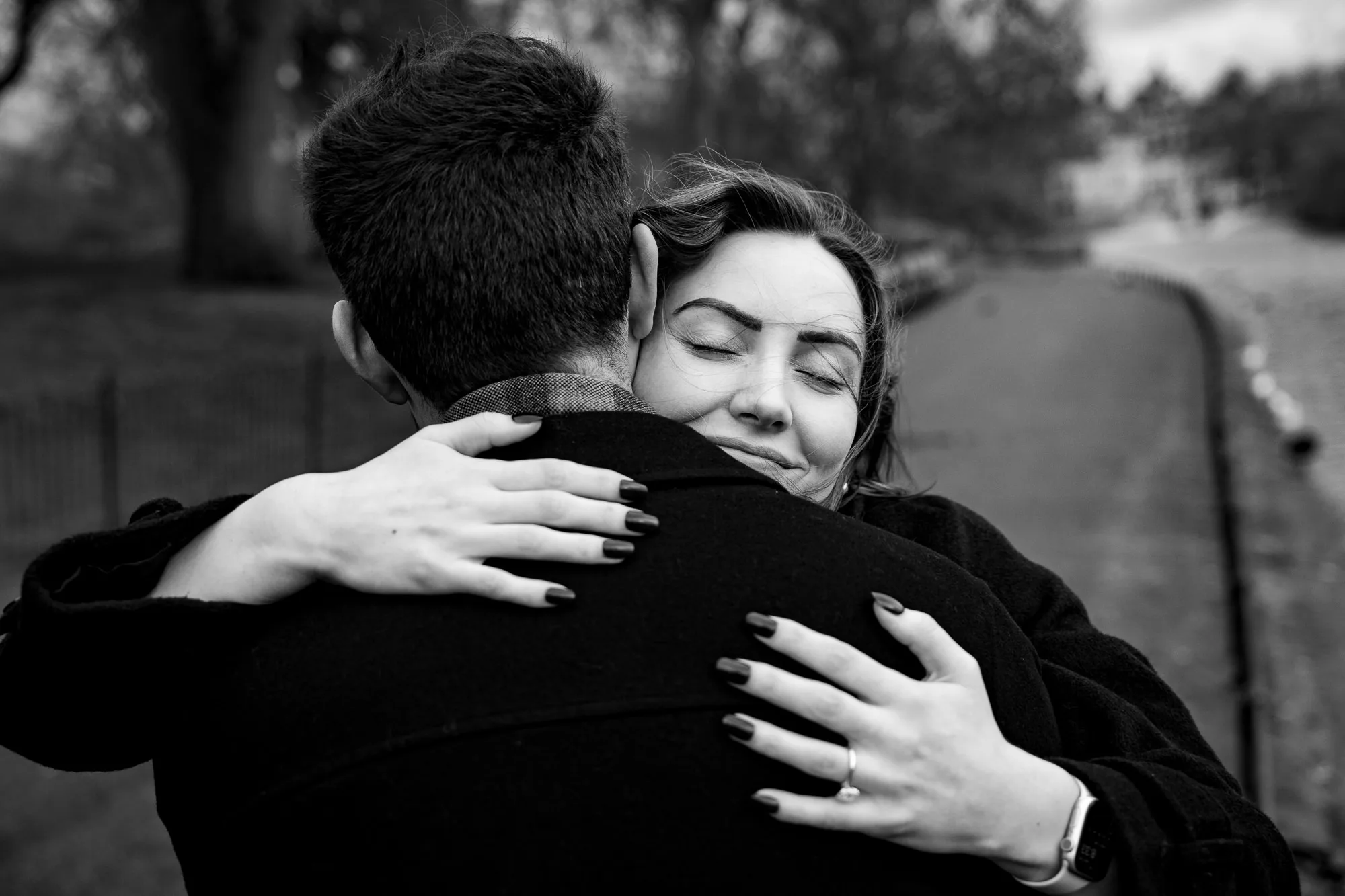 Black and white photo of a women hugging her new fiancé after he proposed to her in St James Park