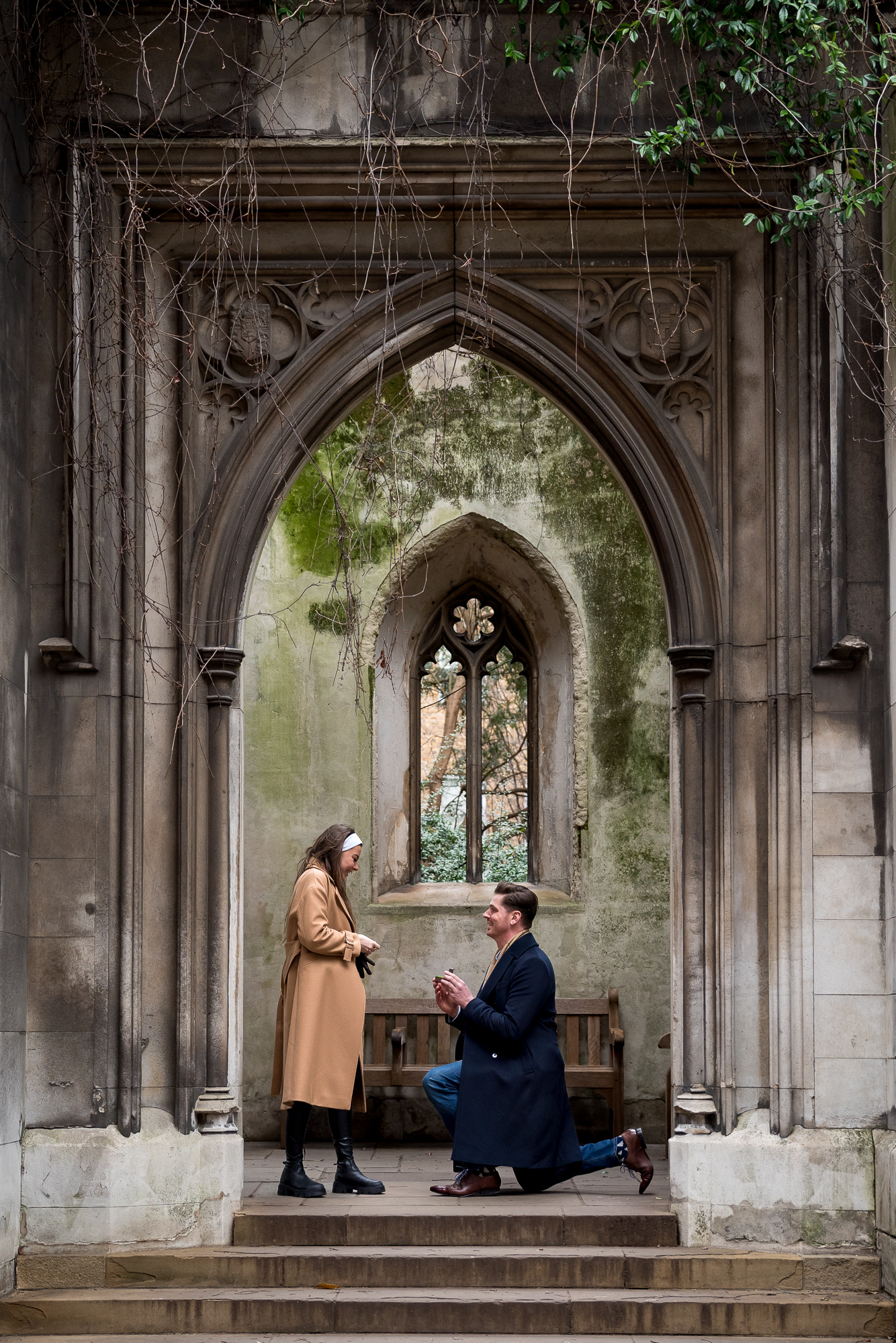 A man proposing to his partner in the archway of the ruined St Dunstans Church in London