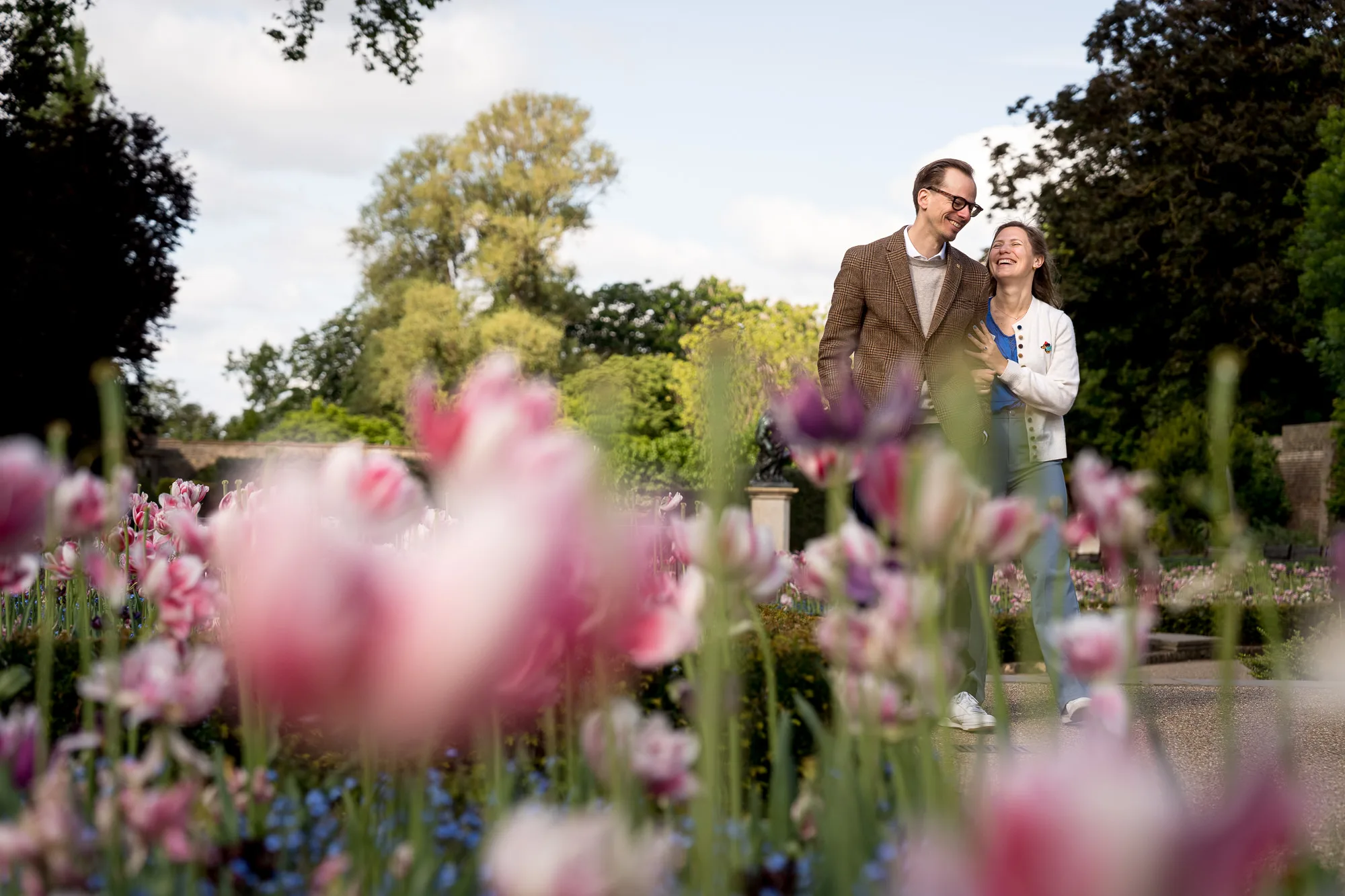 A couple taking engagement photos in Holland Park, surrounded by tulips