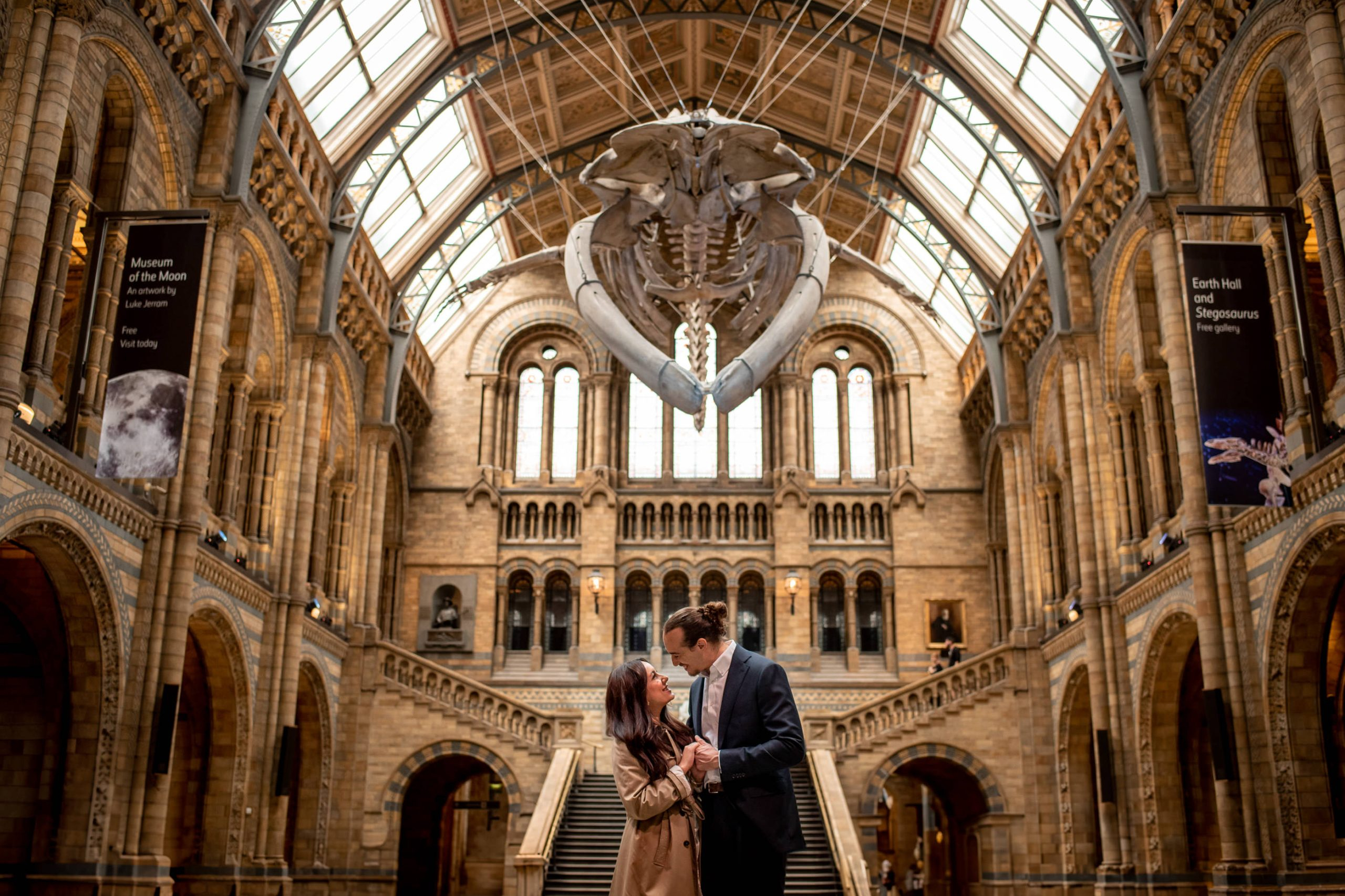 A couple proposing under a giant whale skeleton in the main hall of the Natural History Museum in London