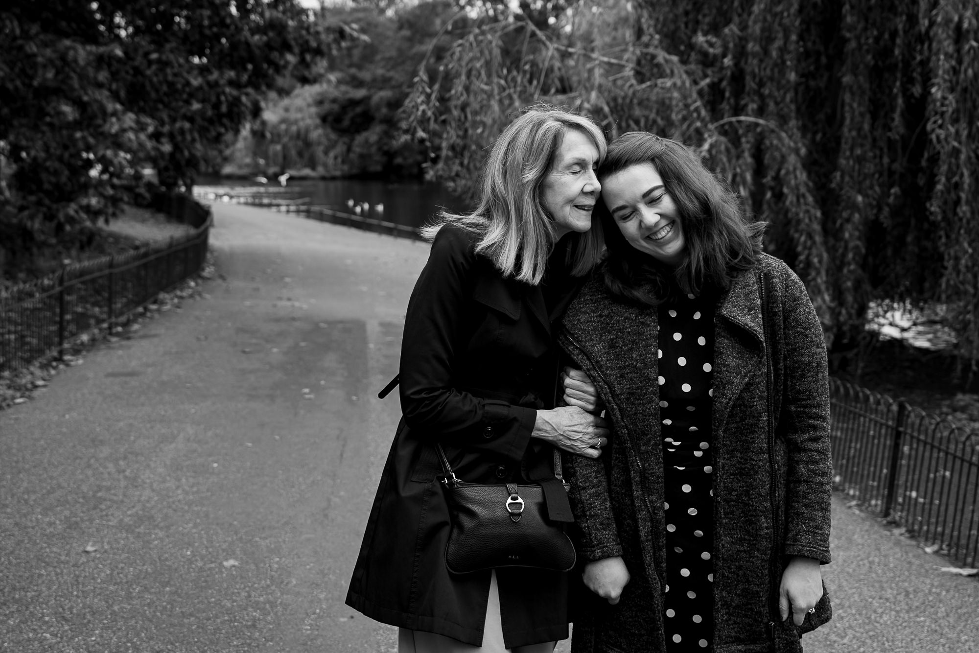 a mum hugs her daughter after her new fiancé proposed to her in St James Park in London. Black and white photo.