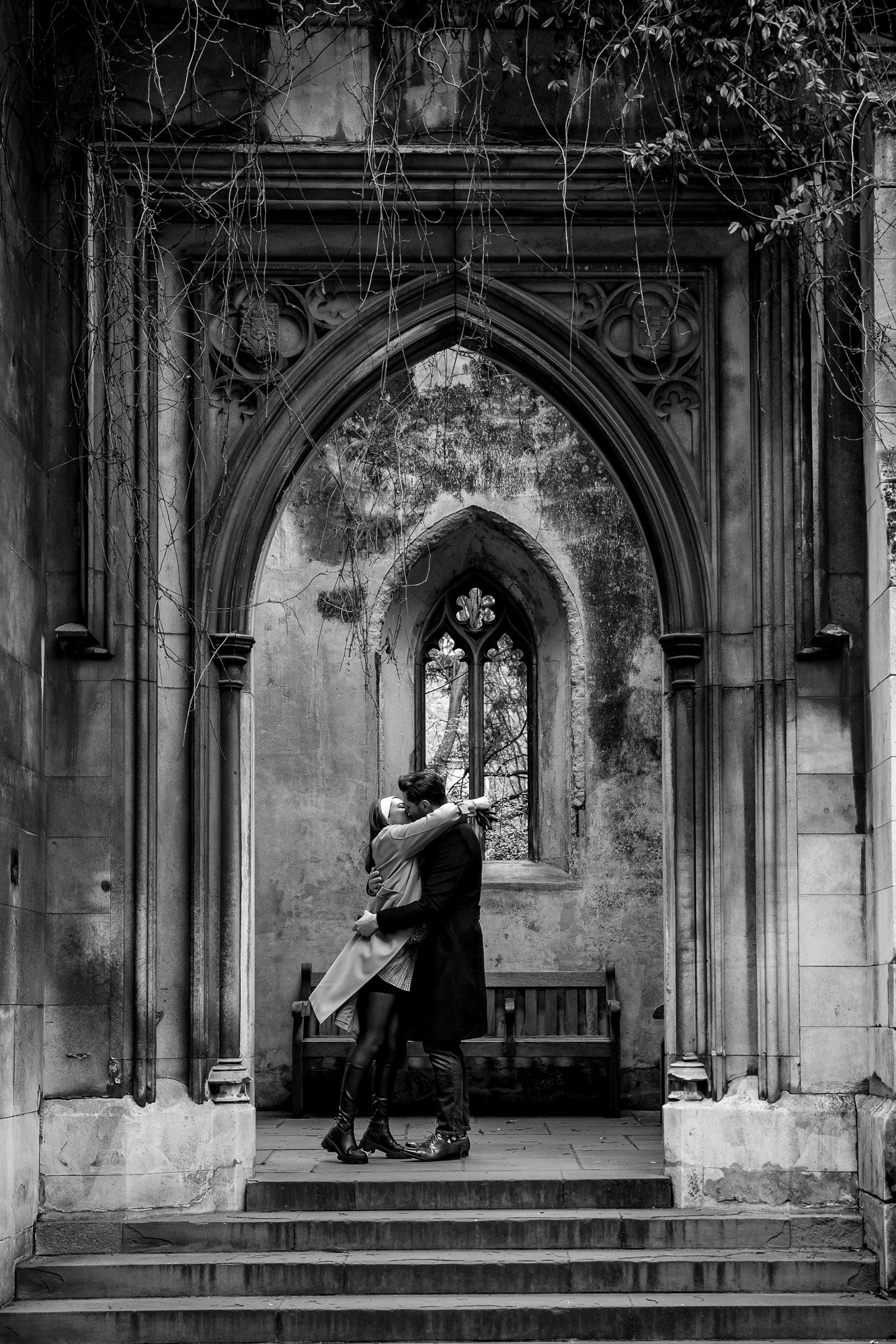 Couple hugging in kissing in the arch of St Dunstan in the east just after their engagement