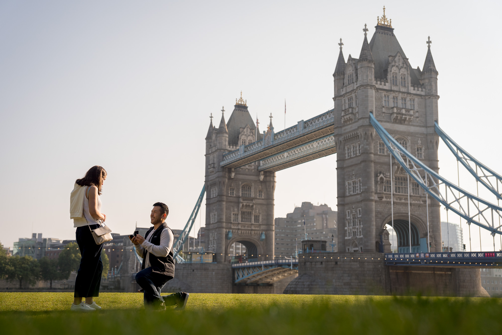 A man proposes to his girlfriend with Tower Bridge in the background
