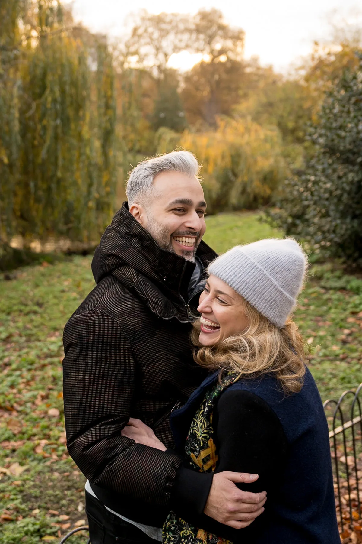A couple hug and laugh after he proses to her during autumn in St James Park in London