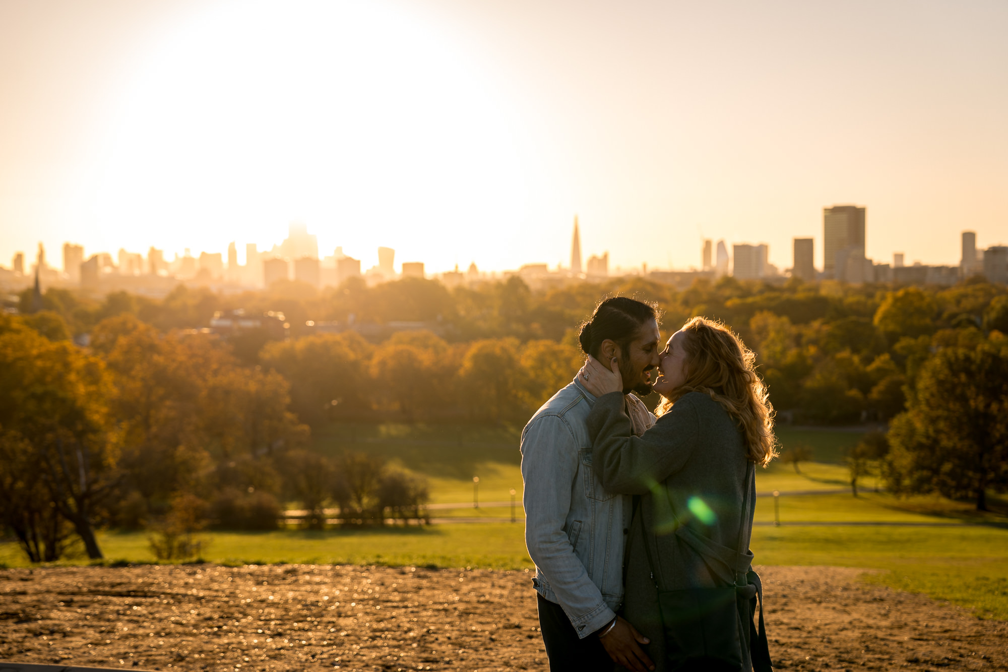 A couple kissing at sunrise on primrose hill with the London skyline in the background