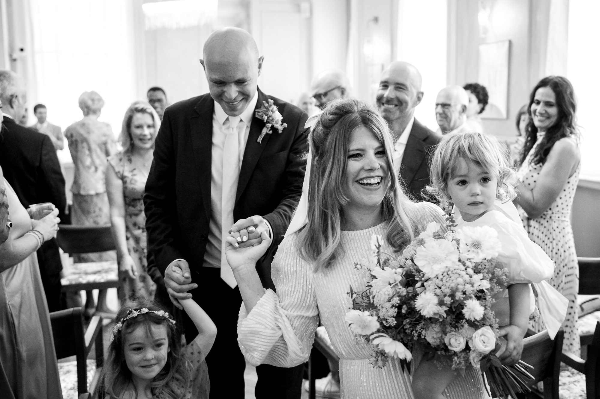 A bride and groom with their kids walking out of their micro wedding ceremony