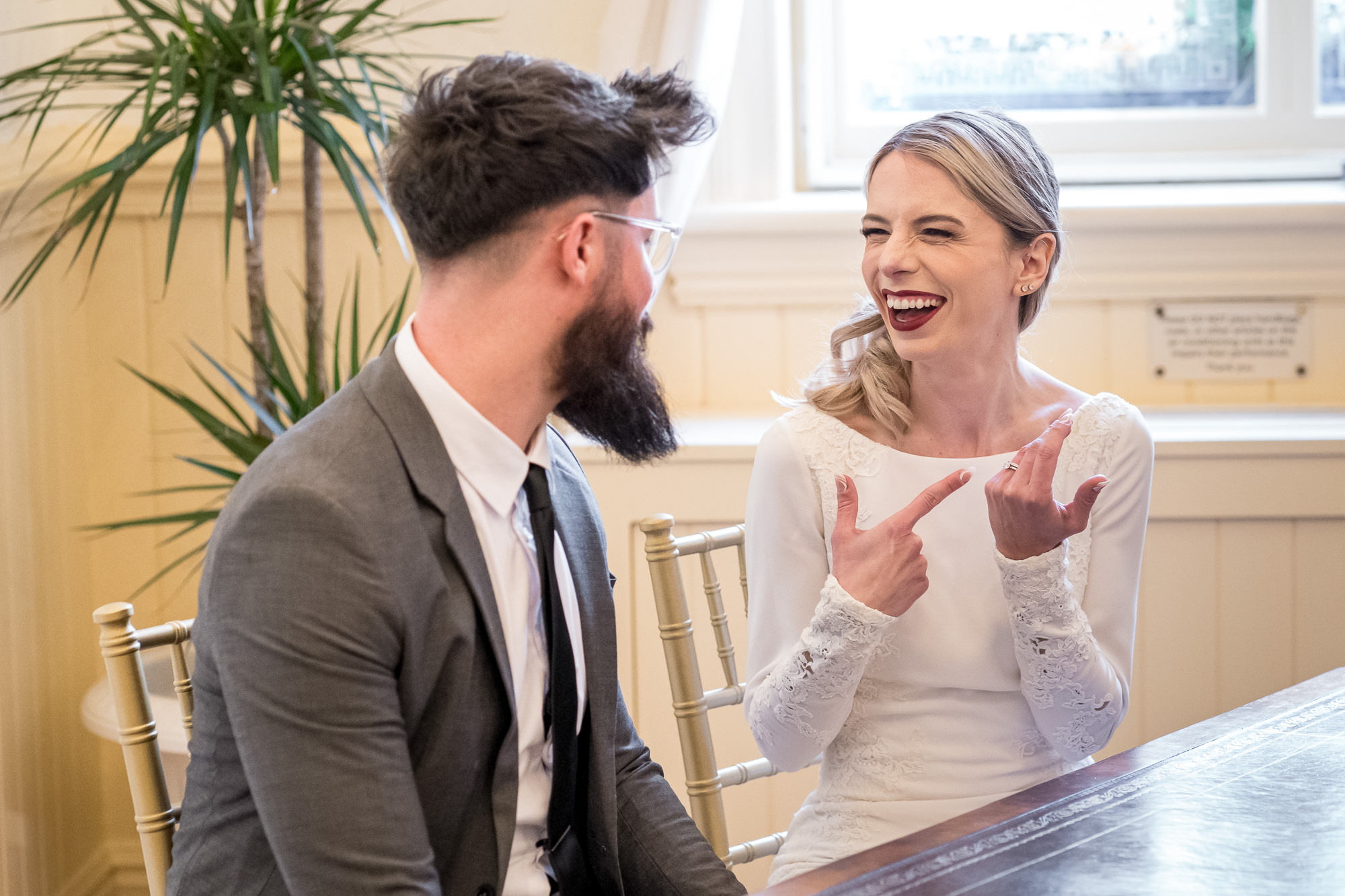 A couple laughing after just getting married and bride is pointing at her ring